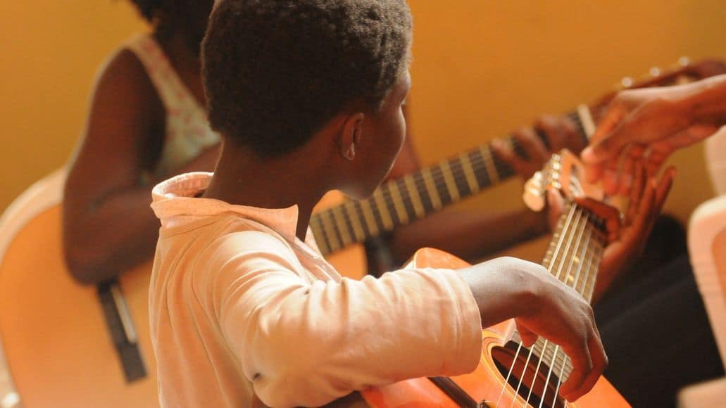 Black boy taking guitar classes in Africa