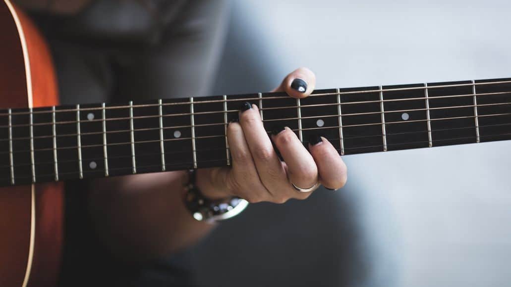 Female guitarist playing chord on guitar